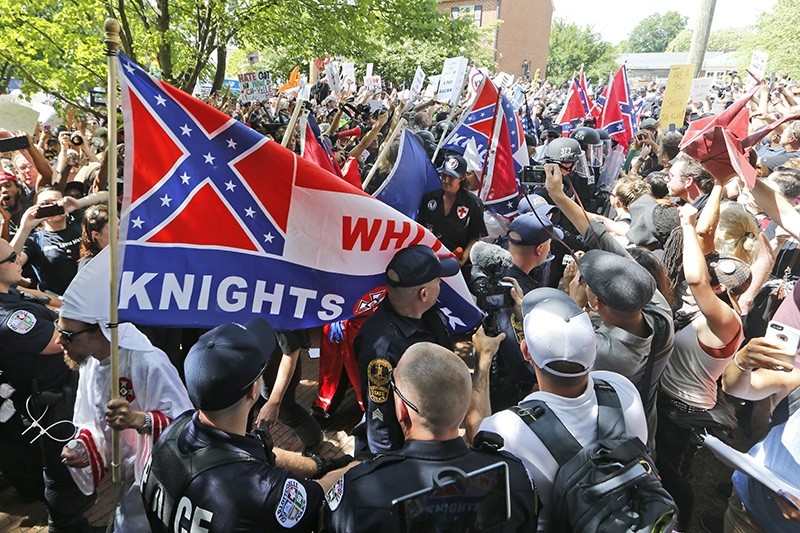 This July 8, 2017 photo shows members of the KKK escorted by police past a large group of protesters during a KKK rally in Charlottesville, Va. (AP Photo)