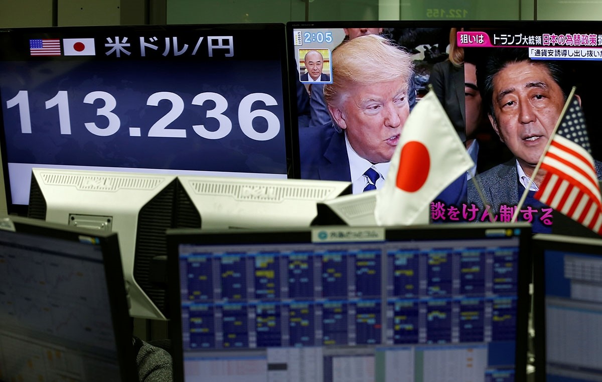 A TV monitor showing U.S. President Donald Trump and Japanese Prime Minister Shinzo Abe is seen next to another monitor showing the Japanese yen's exchange rate against the U.S. dollar at a foreign exchange trading company in Tokyo. (Reuters Photo)