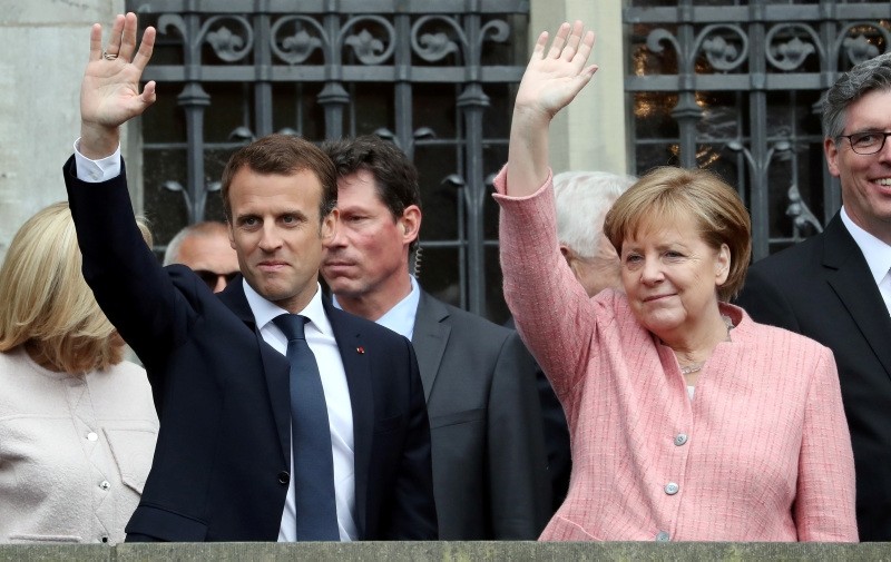 French President Emmanuel Macron (C) greets the crowd next to German Chancellor Angela Merkel (R) at their arrival to the Charlemagne Prize (Karlspreis) ceremony at the town hall in Aachen, Germany, 10 May 2018 (EPA Photo)