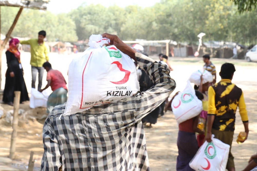 A Rohingya man carries an aid pack donated by Red Crescent.