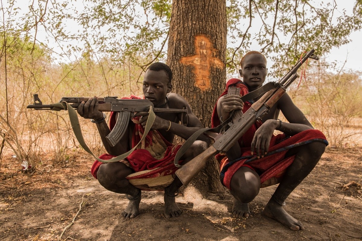 Cattle keepers Achiek Butich (left) and Makal Maker pose with their weapons, used to protect their herds in a nation where conflict has broken out in recent years.