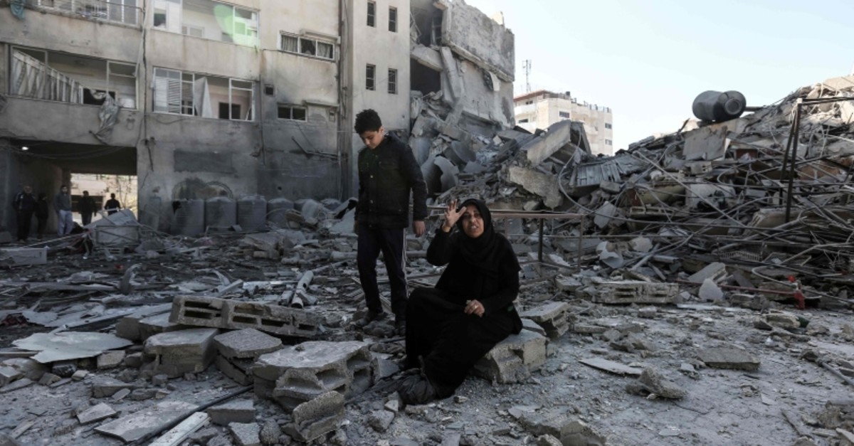 Photo on March 26, 2019, shows a Palestinian woman sitting next to the rubble of a building in Gaza City, after Israeli airstrikes hit dozens of sites across the Strip overnight in response to rocket fire from the Palestinian enclave. (AFP Photo)