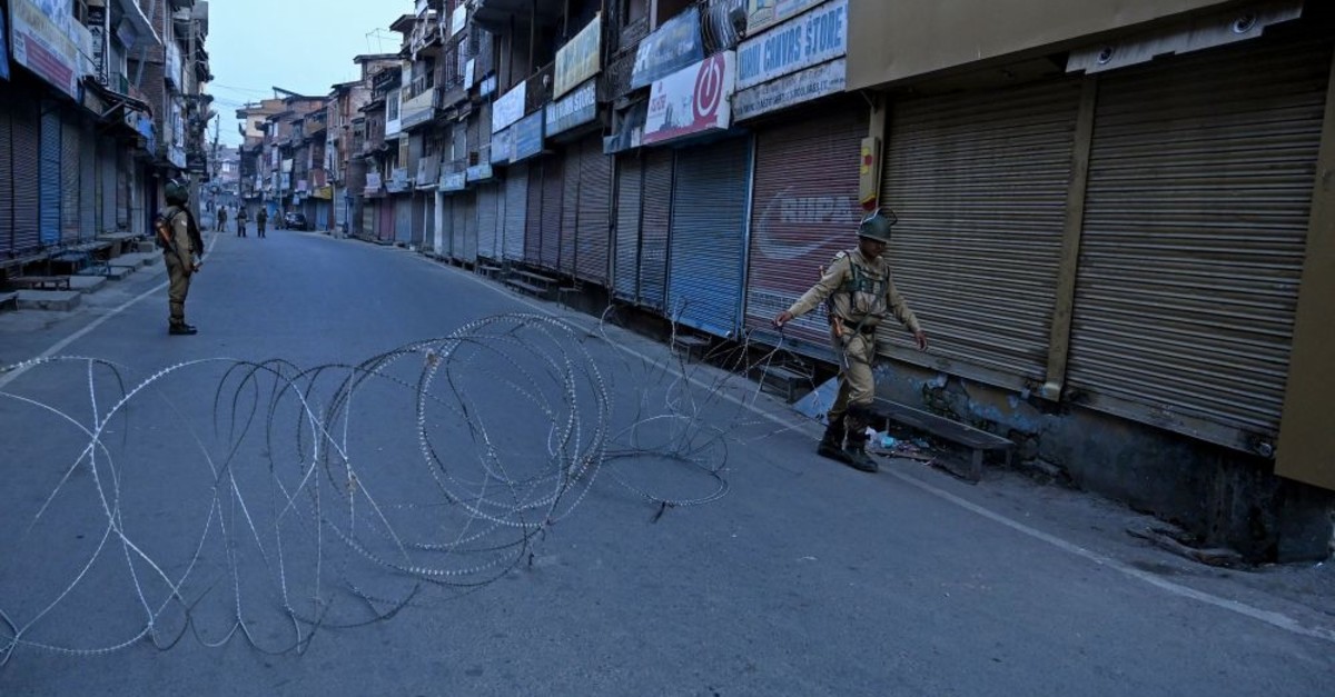 An Indian paramilitary soldier unfolds barbed wire to block a road during restrictions in Srinagar, Kashmir, Sept. 27, 2019. 
