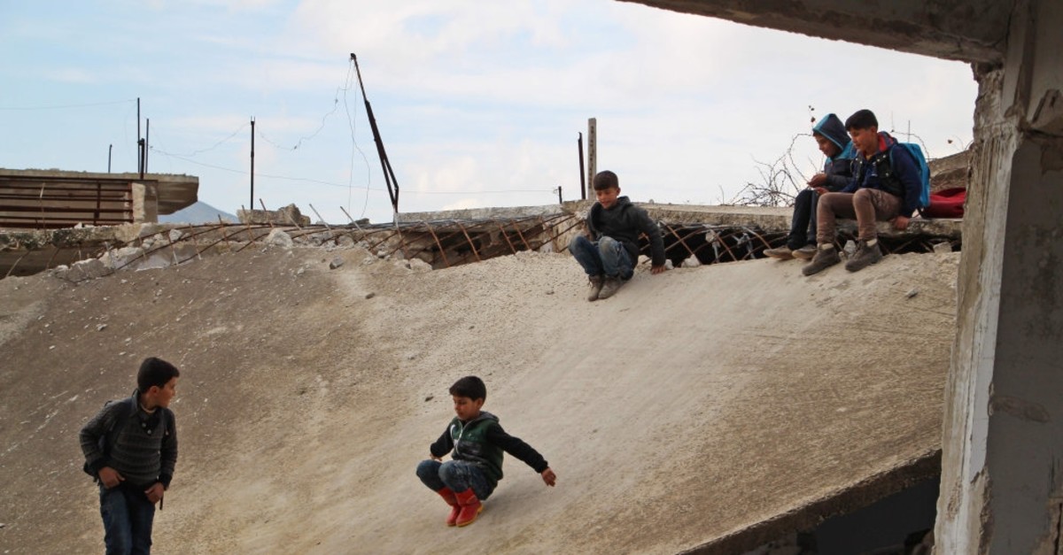 Syrian children slide down the collapsed roof of a bombarded school in Idlib province, Jan. 30, 2019.