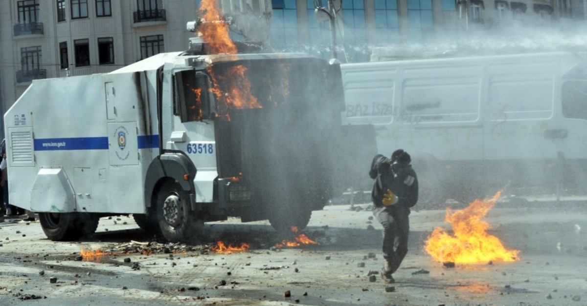 A rioter wearing a gas mask runs after rioters set a police vehicle on fire at Taksim Square adjacent to Gezi Park, June 11, 2013.