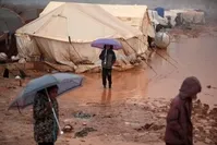 Syrian children who fled battles in the southern countryside of the Idlib province walk in mud and water caused by heavy rainfall, in a camp for displaced people in Kafr Dariyan situated at a short distance from Syria's border with Turkey, on Dec. 28, 2019 (AFP Photo)