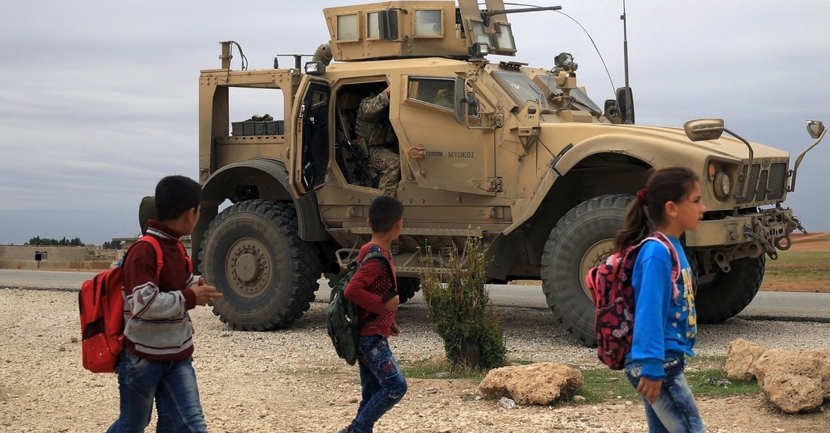 Syrian schoolchildren walk past U.S. troops on patrol close to the Turkish border in al-Hasakah, Nov. 4, 2018. 