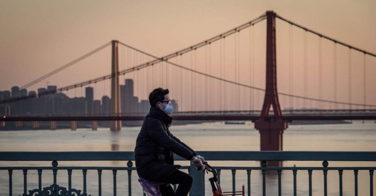 A man wearing a protective face mask rides a bicycle in Wuhan in China's central Hubei province, Feb. 17, 2020. (AFP Photo)