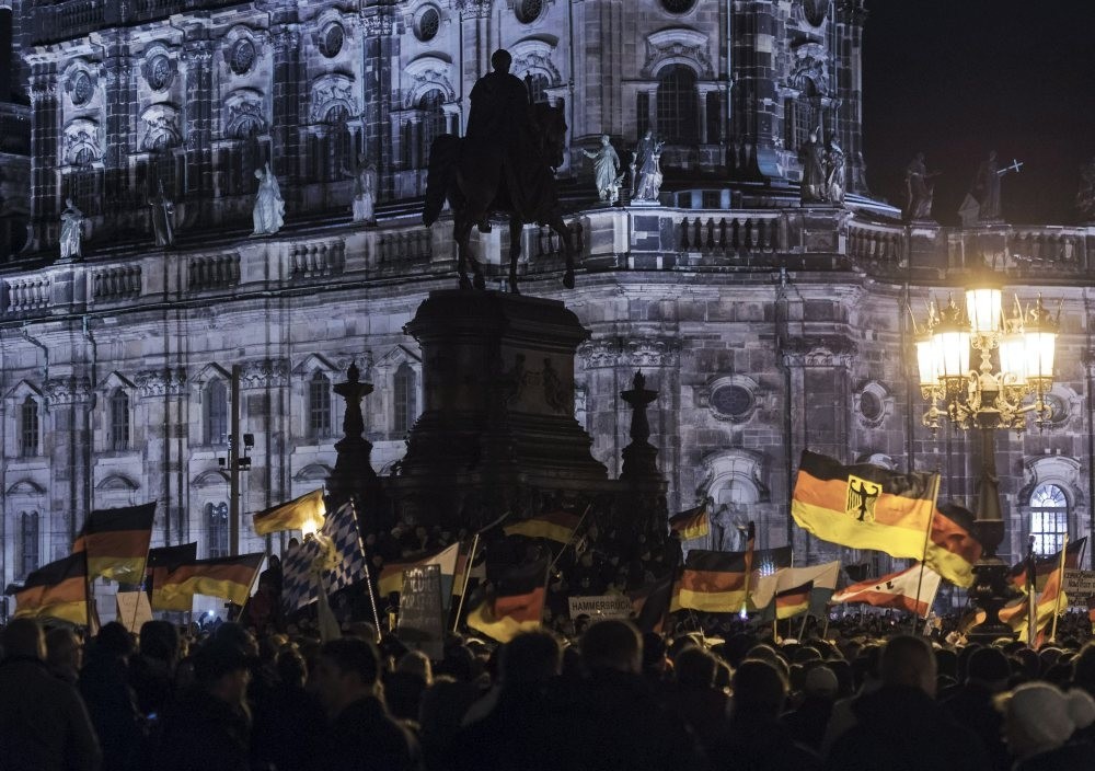 Far-right protesters holding German flags participate in a rally against Islam, in front of the bronze equestrian statue of King John of Saxony, Dresden, Dec. 22, 2014. 