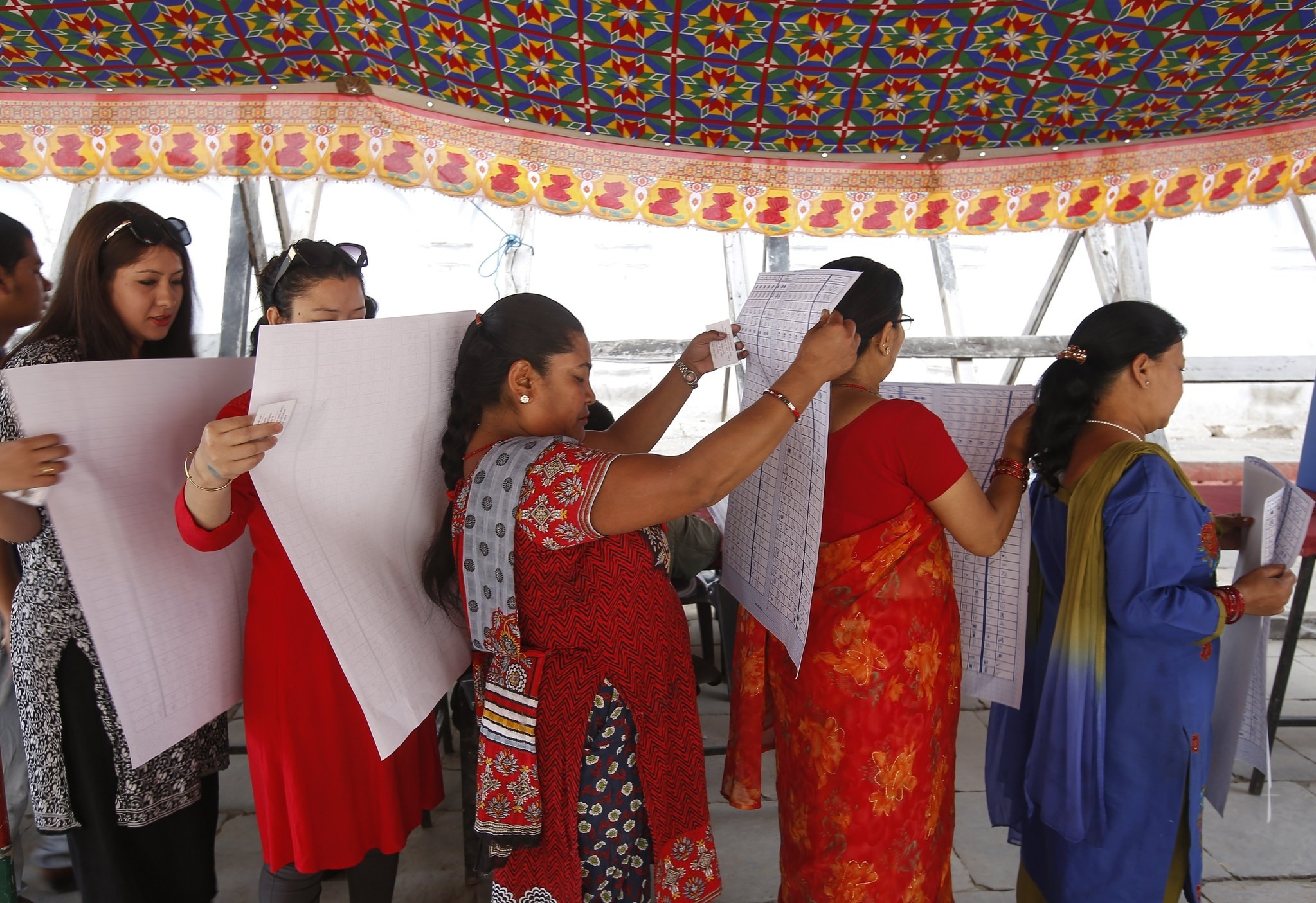 Nepalese women read polling information prior to casting their ballot at a polling station in Kathmandu Durbar Square in Kathmandu, Nepal, 14 May 2017. (EPA Photo)