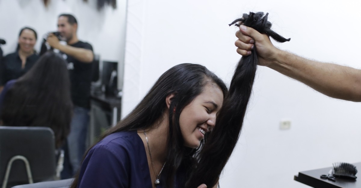 Valery Du00edaz holds the hair she had cut off to earn $100 in Caracas, April 5, 2019.