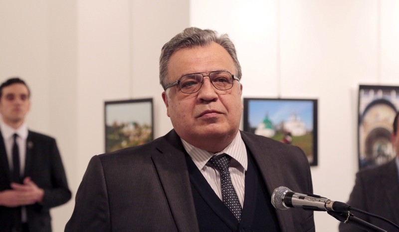 This file photo shows Andrei Karlov, late Russian ambassador to Turkey, speaking at a gallery in Ankara on Dec. 19, 2016, shortly before a gunman, seen at the rear on the left and posing as a bodyguard, shot him dead. (AP Photo)