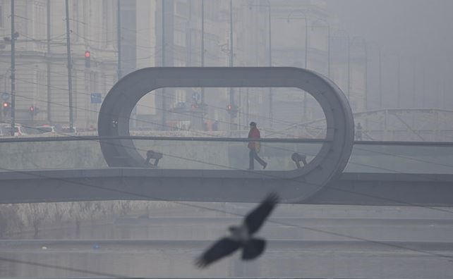 A man crosses a bridge in Sarajevo, Bosnia, as a pollution smog lies over the city on Dec. 22, 2016. (AP File Photo)