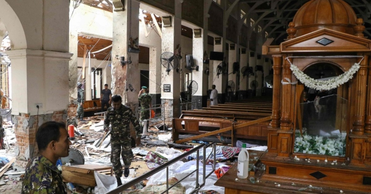 / Sri Lankan security personnel walk past dead bodies covered with blankets amid blast debris at St. Anthony's Shrine following an explosion in the church in Kochchikade in Colombo on April 21, 2019 (AP Photo)