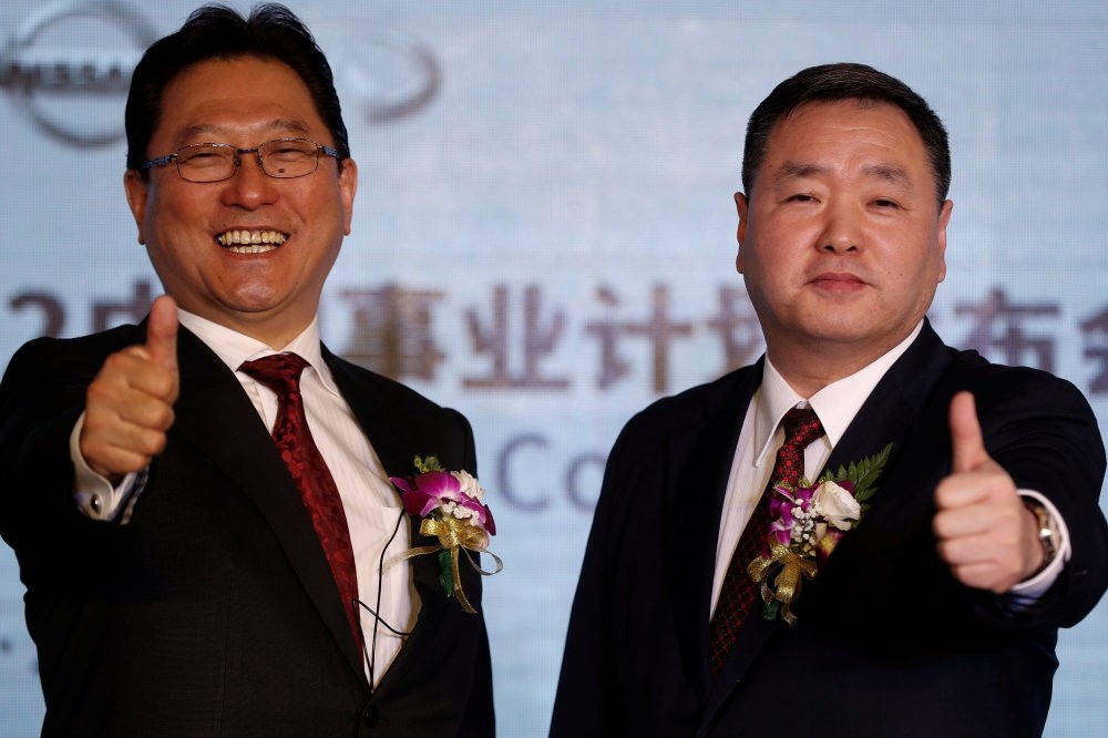 Jun Seki (L), the president of Dongfeng Motor Co., the Nissan and Dongfeng Group joint venture, and its Executive Vice President Lei Ping give the thumbs-up during a news conference in Beijing.