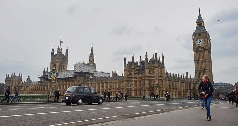 Pedestrians cross Westminster Bridge in the shadow of the Houses of Parliament in central London (AFP File Photo