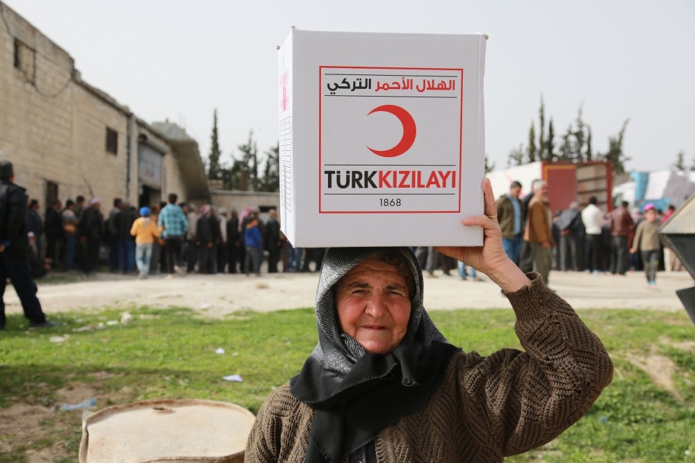 A local resident of Syria's Afrin carries a humanitarian aid package from the Turkish Red Crescent, March 31.