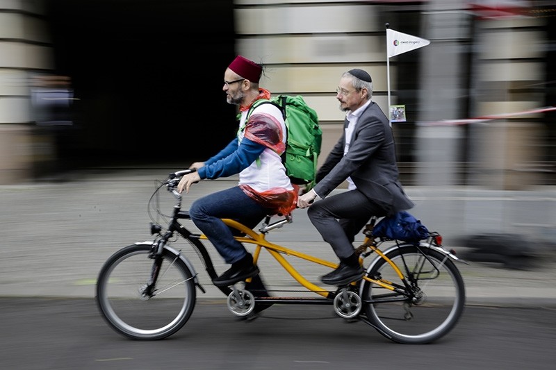 A Muslim and a Jewish man rides a tandem together during a bicycle tandem tour of Jews and Moslems against anti-Semitism and hatred of Muslims in Berlin, Sunday, June 24, 2018. (AP Photo)