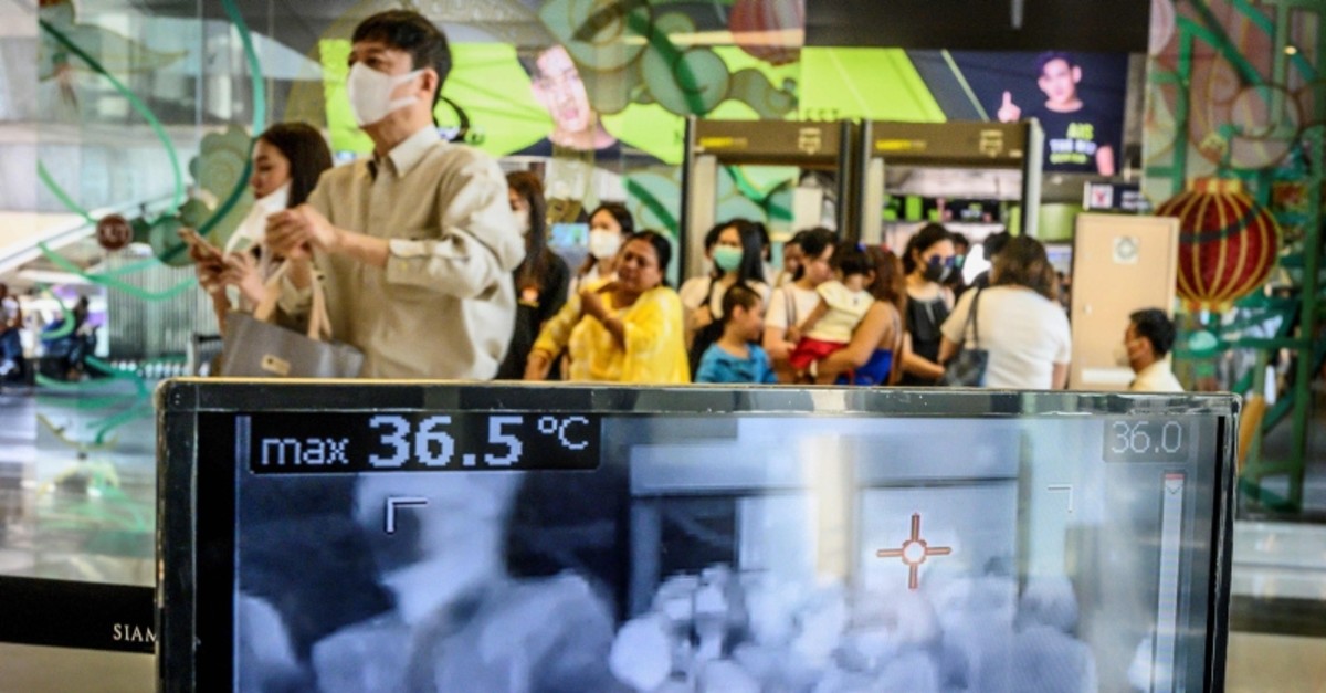 People with protective face masks pass in front of a thermal scanner as they enter a shopping mall in Bangkok on January 29, 2020 (AFP Photo)