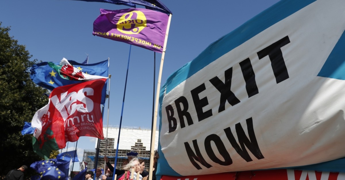 Remain and leave supporters wave flags and hold banners during a demonstration outside the gates of Parliament in London, Sept. 4, 2019.