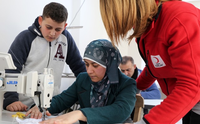 A Red Crescent worker shows a Syrian woman how to sew at a workshop in İzmir, Mar. 1, 2019.