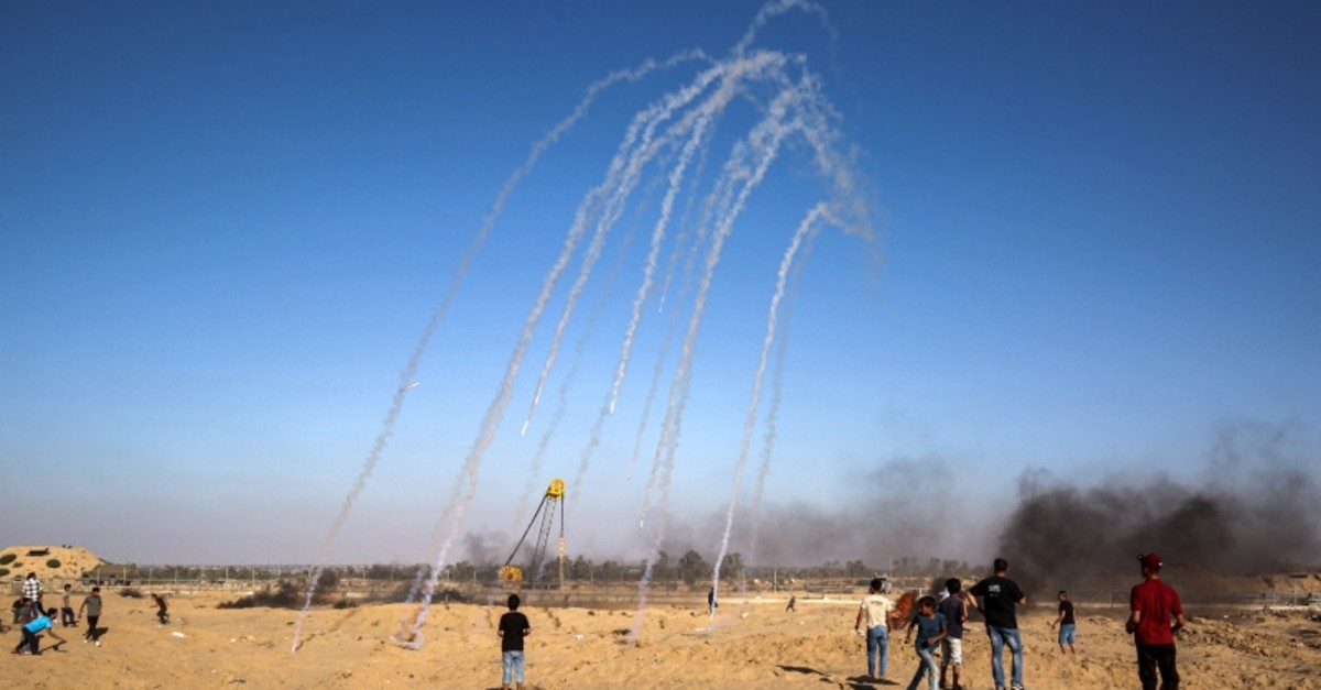 Tear gas canisters fired by Israeli forces across the fence fall amongst Palestinian protesters demonstrating along the border near Rafah in the southern Gaza Strip on July 19, 2019. (AFP Photo)