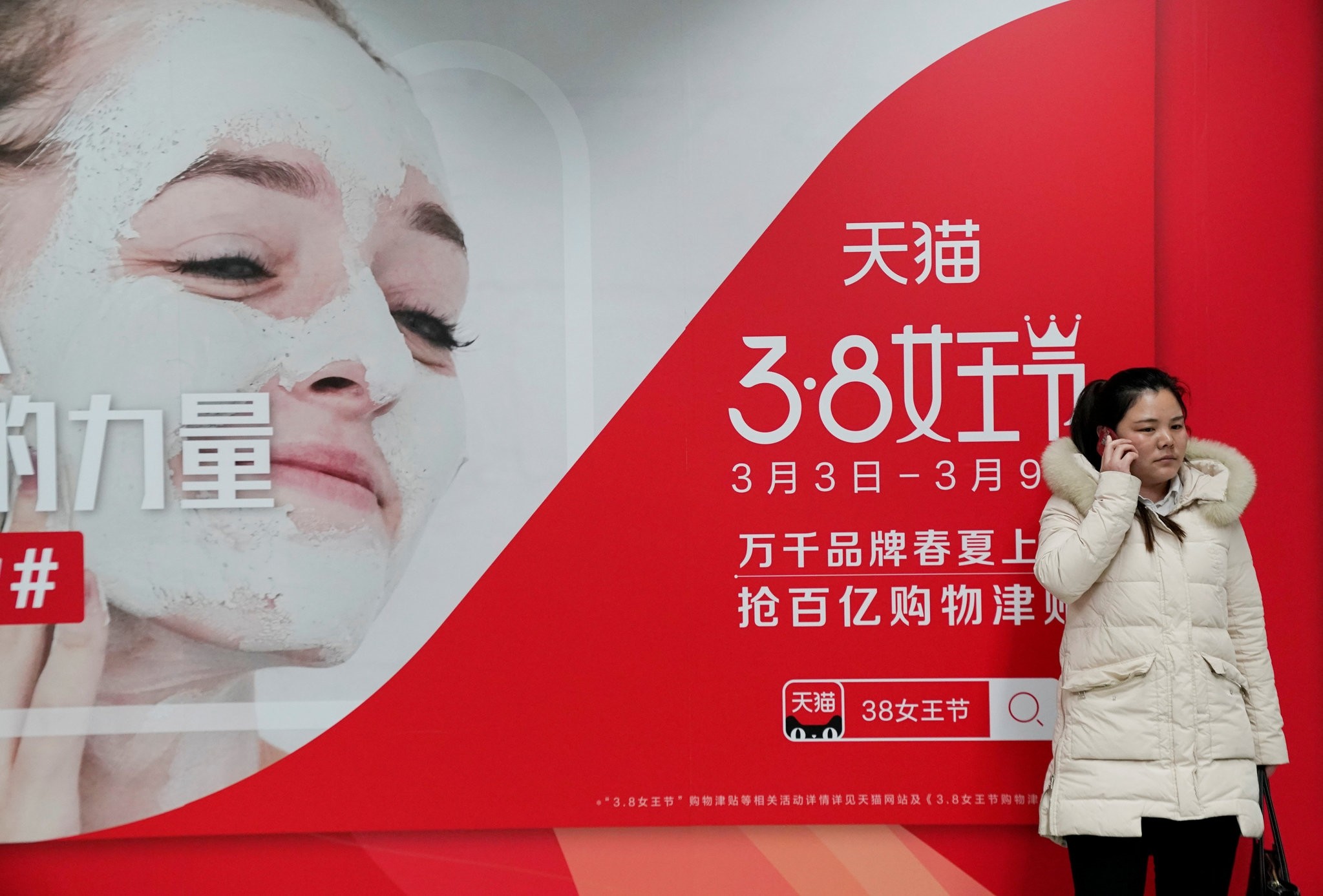 A woman stands in front of an International Womenu2019s Day advertisement by Tmall, Alibabau2019s e-commerce platform, at a subway station in Beijing.