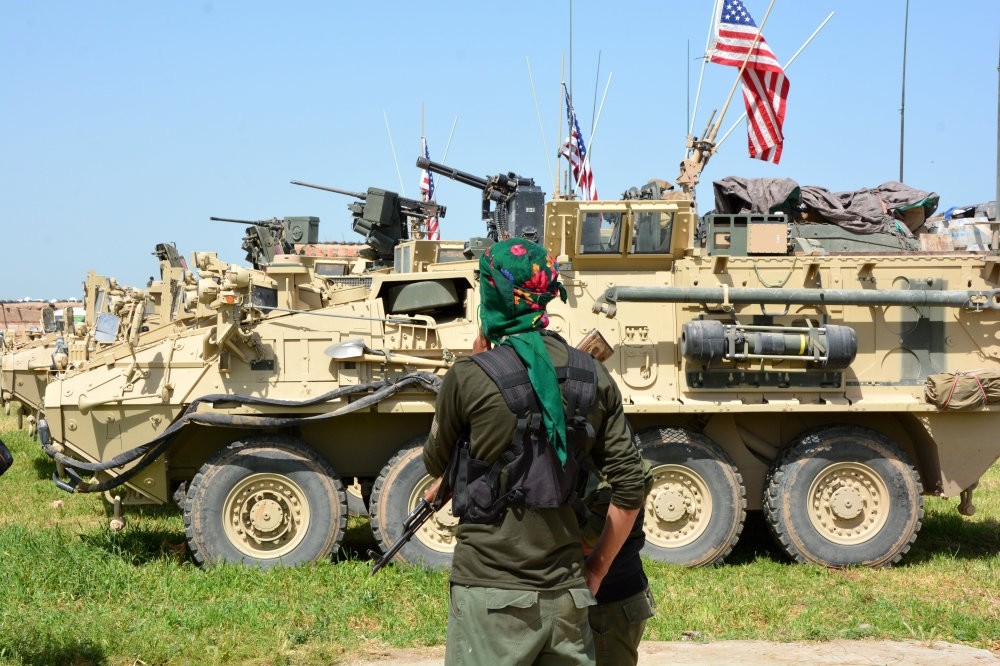 A YPG terrorist stand next to American eight-wheeled armored vehicles, near the Syrian-Turkish border on April 29.