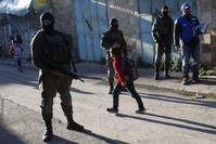 Palestinian children walk past Israeli soldiers on their way to school in the West Bank city of Hebron, Feb. 12, 2019.  (AP Photo)
