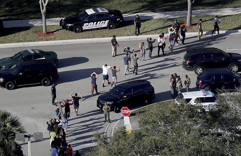 In this Feb. 14, 2018 file photo,  students hold their hands in the air as they are evacuated by police from Marjory Stoneman Douglas High School in Parkland, Fla., after a shooter opened fire on the campus. (AP Photo)