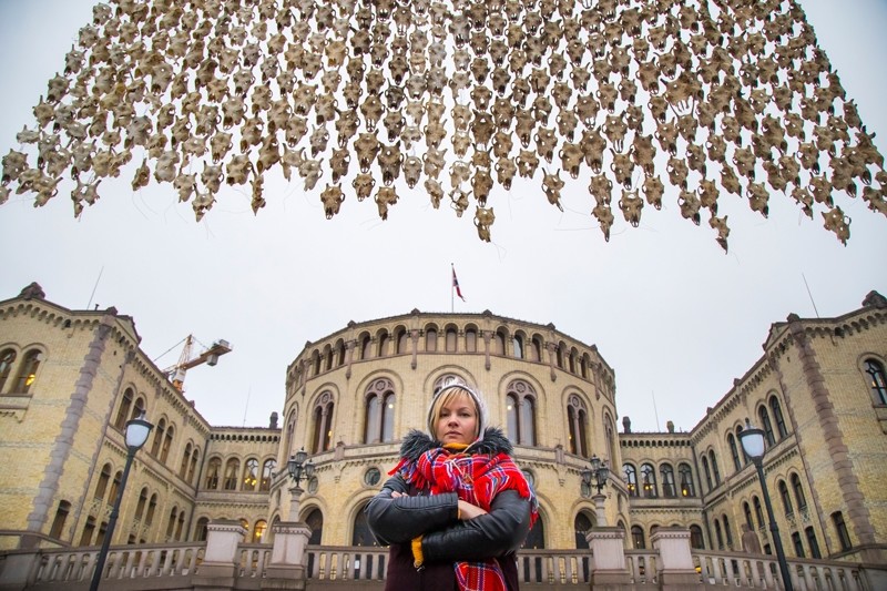 Sami artist Maret Anne Sara stands near her art piece of 400 reindeer skulls hanging in front of the Parliament building in Oslo, Norway ( AP Photo)