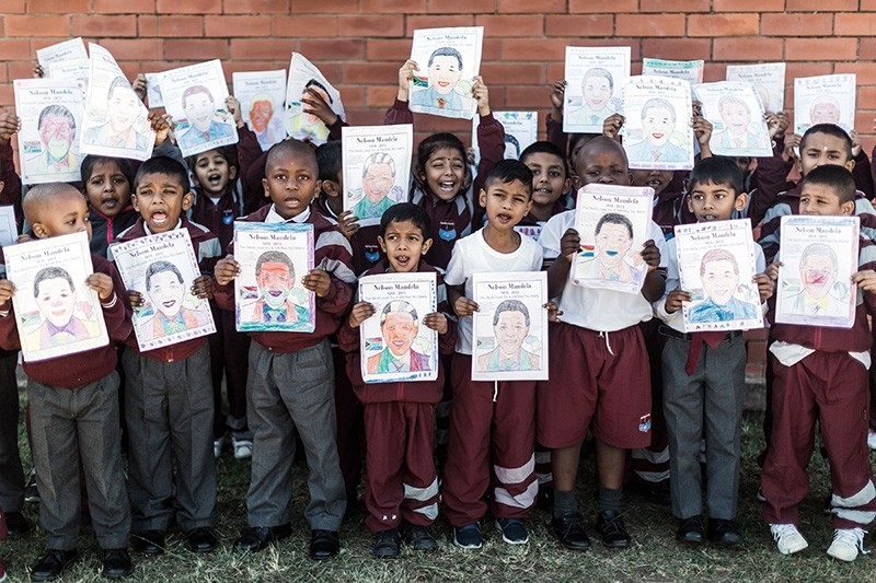 A group of Grade R learners from Northlen Primary school hold posters of former president Nelson Mandela as they sing 