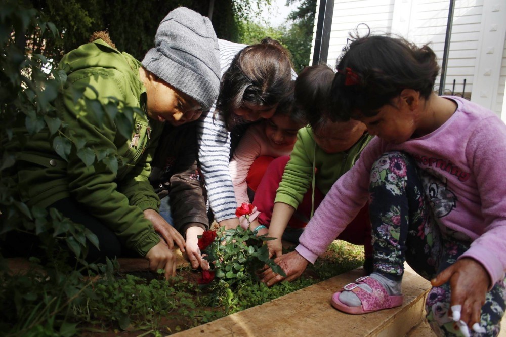 Children plant roses during their first outing in months.