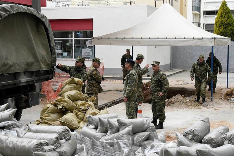 Military officers unload sacks of sand next to a hole in the ground (R), where a 250 kg World War Two bomb was found during excavation works at a gas station. (Reuters Photo)