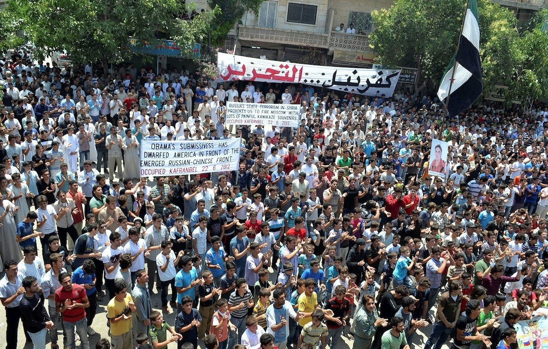 A handout image released by the Syrian opposition's Shaam News Network shows anti-regime demonstrators holding banners and clapping during a protest in Kfar Nubul, in the northern province of Idlib, on June 22, 2012.