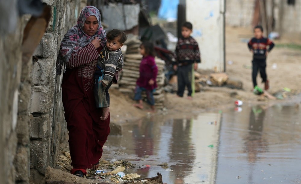 A Palestinian woman carrying her child walks on a rainy day in the southern Gaza Strip, Dec. 30.