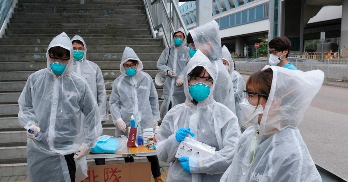 Residents wearing masks and raincoats volunteer to take temperature of passengers following the outbreak of a new coronavirus at a bus stop at Tin Shui Wai, a border town in Hong Kong, China February 4, 2020. REUTERS/Tyrone Siu