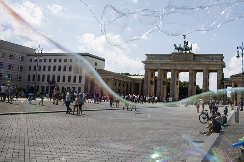 An artist perfoms with soap bubbles in front of the 'Brandenburg Gate' in Berlin, Germany, 30 July 2017. (EPA Photo)