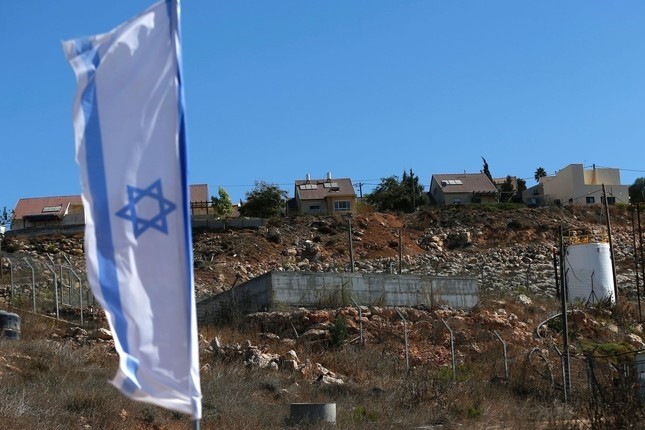 A picture taken on October 2, 2016 shows an Israeli national flag flying next to an Israeli building site of new housing units in the Jewish settlement of Shilo in the illegally occupied Palestinian West Bank. (AFP Photo)