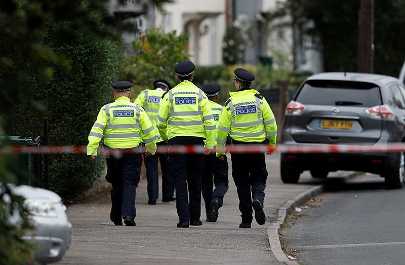 Police officers walk behind cordon tape set up around a property being searched after a man was arrested in connection with an explosion on a London Underground train (Reuters Photo)