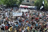 A handout image released by the Syrian opposition's Shaam News Network shows anti-regime demonstrators holding banners and clapping during a protest in Kfar Nubul, in the northern province of Idlib, on June 22, 2012.