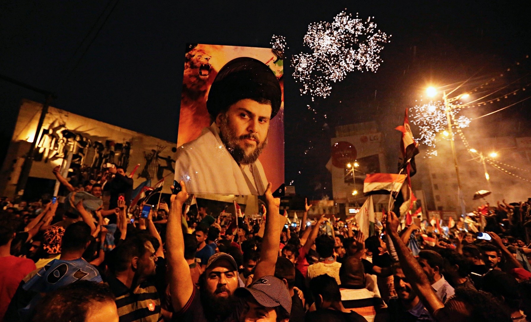 Supporters of Shiite cleric Muqtada al-Sadr, carry his image as they celebrate in Tahrir Square, Baghdad, Iraq.