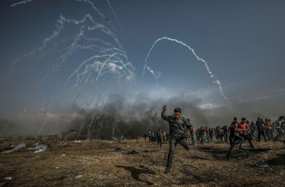 Palestinian protesters run for cover from teargas fired by Israeli soldiers after Friday's protests near the border with Israel, Gaza Strip, April 27.