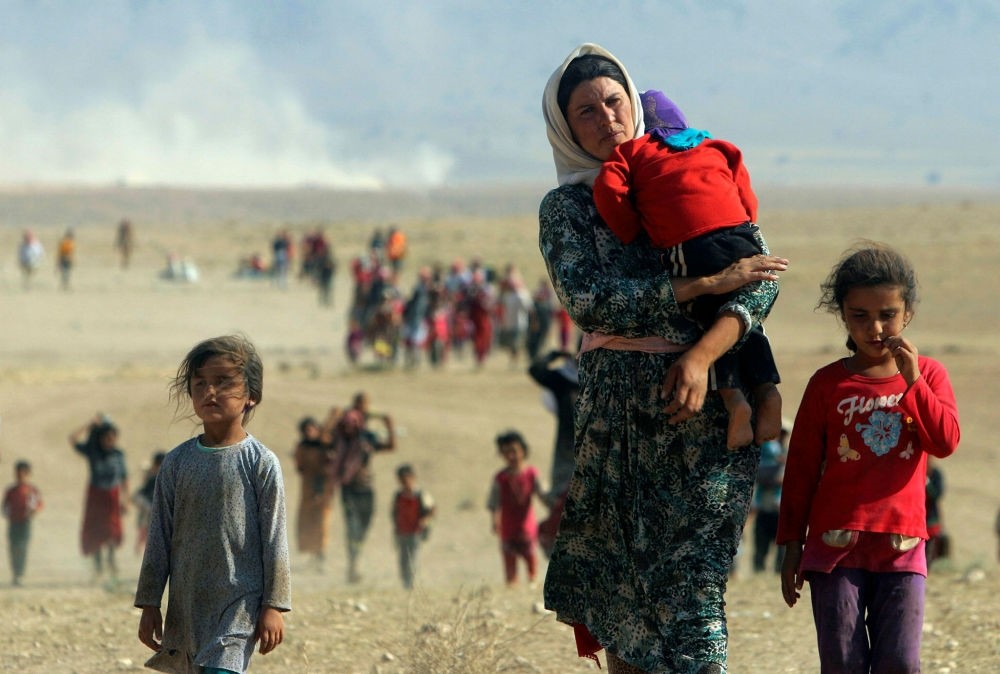 Displaced people from the minority Yazidi sect flee violence from forces loyal to Daesh in Sinjar, walk towards the Syrian border on the outskirts of the Sinjar Mountains.