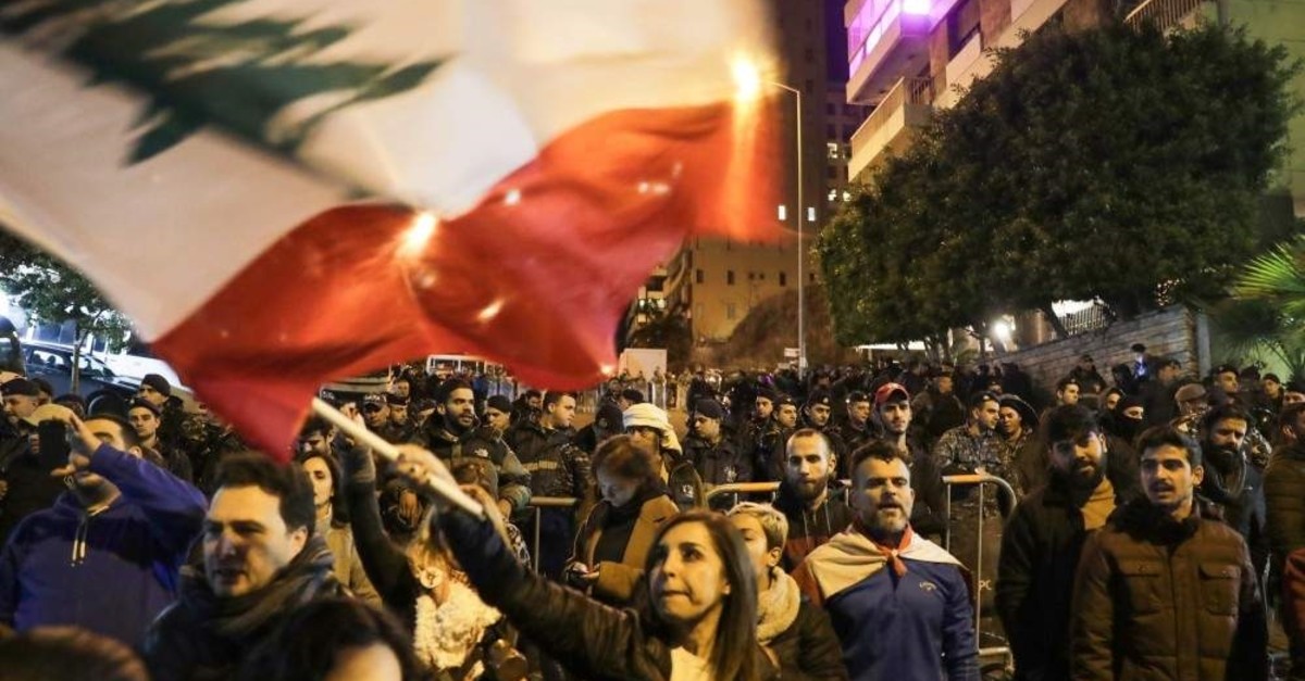 Lebanese protesters wave the national flags as they gather outside the house of Lebanon's new prime minister in the capital Beirut, calling for his resignation less than 10 days after he was appointed, Dec. 28, 2019. (Photo by ANWAR AMRO / AFP)