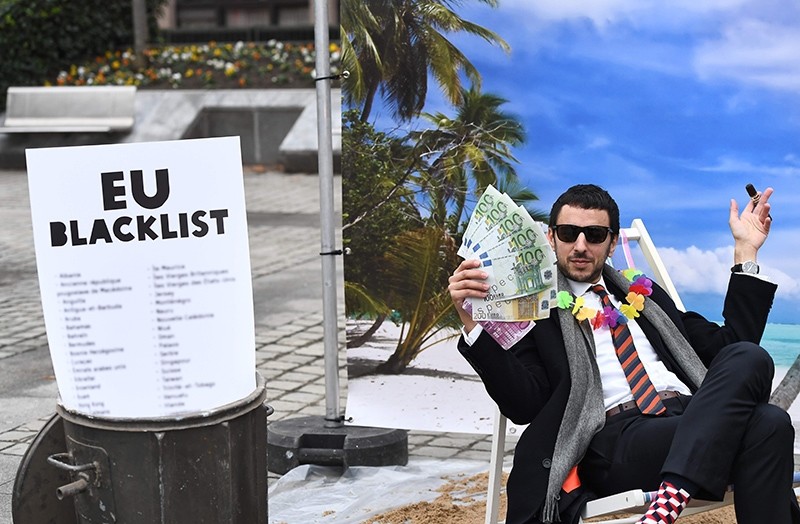 An Oxfam activist stages a satirical street-play mimicking a wealthy person hidding his money in a tax haven near the EU in Brussels, Belgium, Dec. 5, 2017. (AFP Photo)
