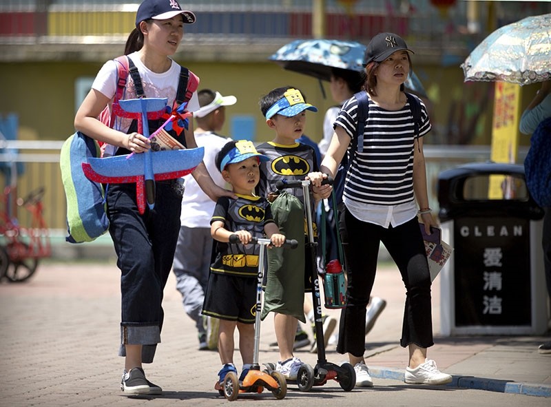 In this June 1, 2018, photo, women walk with children wearing matching outfits at a public park on International Children's Day in Beijing. (AP Photo)