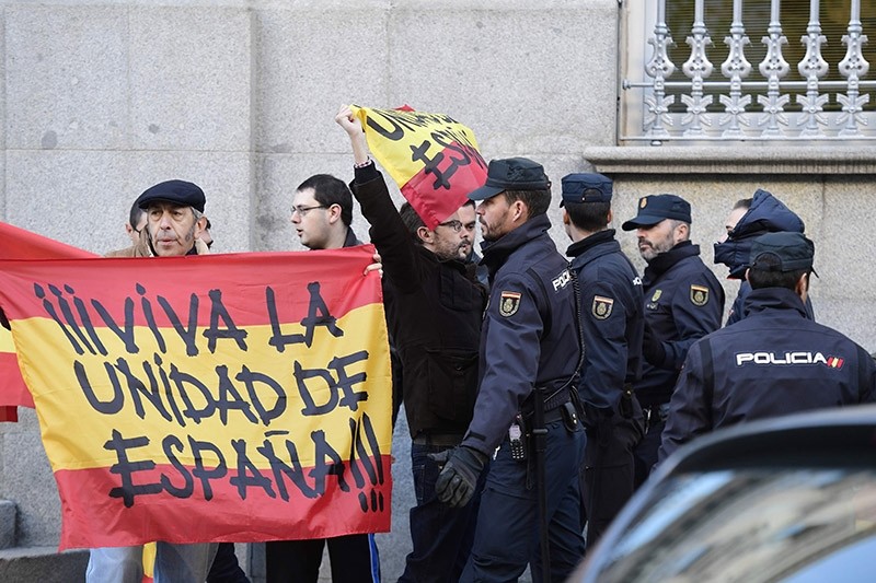 Spanish police stand guard next to two men holding Spanish flags reading ,Long live Spanish unity, as the former speaker of Catalonia's sacked parliament arrives at the Supreme Court in Madrid on November 9, 2017. (AFP Photo)