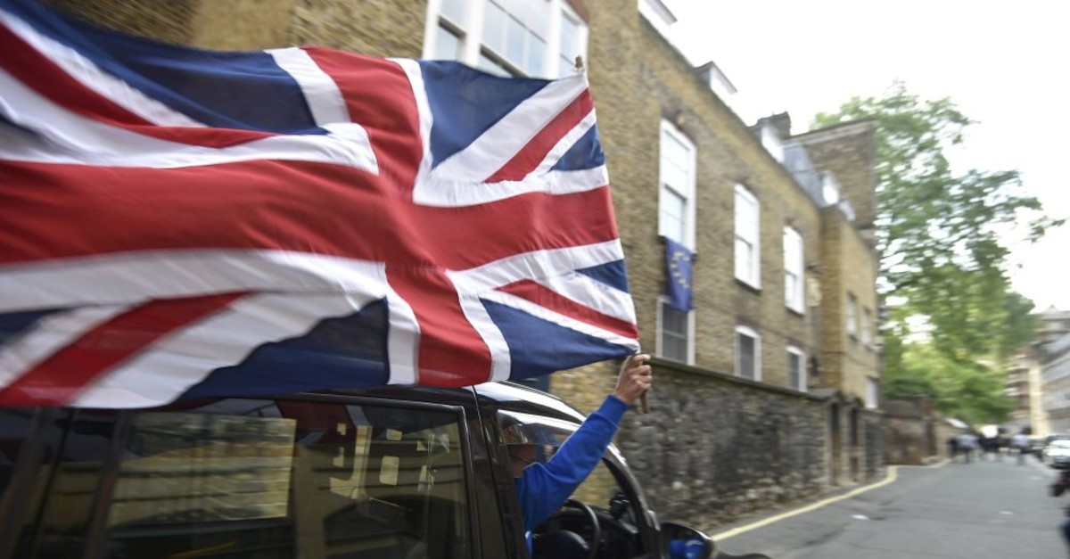 A taxi driver holds a U.K. flag as he celebrates following the result of the EU referendum, London, June 24, 2016.