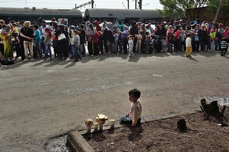 A child sits near migrants and refugees waiting in line at the railroad station in the makeshift camp at the Greek-Macedonian border near the village of Idomeni on April 19, 2016 (Reuters File Photo)